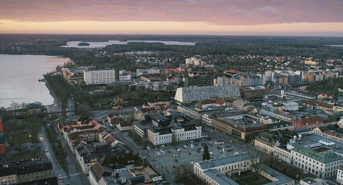 Två barn sitter på golvet och tittar i en mobil med ett leende