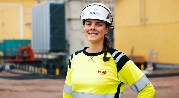 Medarbetaren Tina st&aring;r i gul tr&ouml;ja och tittar in i kameran